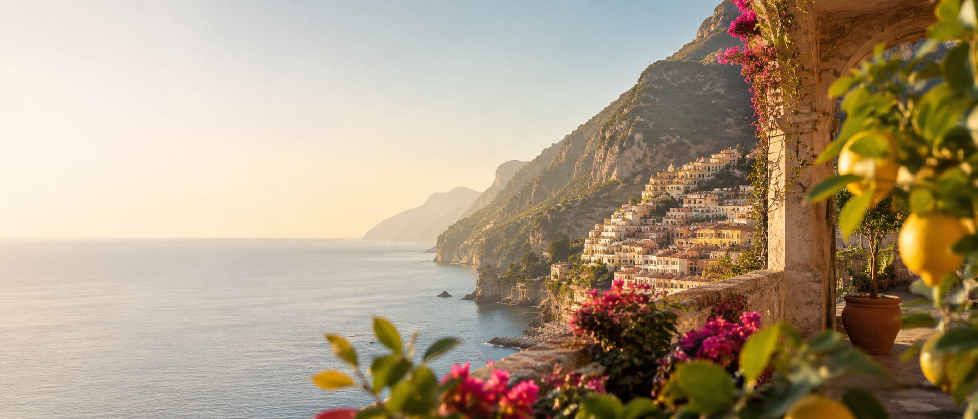 La Costiera Amalfitana in luce dorata, vista da una terrazza tra limoni e bouganville